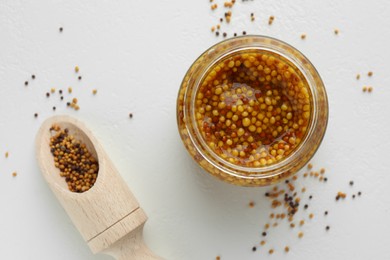 Photo of Fresh whole grain mustard in bowl and dry seeds on white table, flat lay