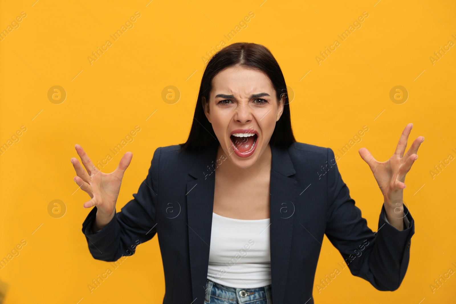 Photo of Angry young woman on yellow background. Hate concept