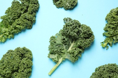 Photo of Fresh kale leaves on light blue background, flat lay