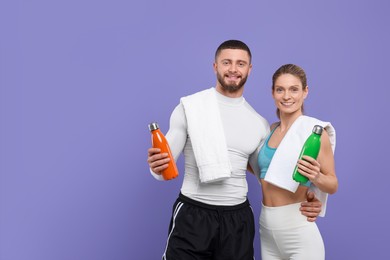 Athletic people with thermo bottles and towels on purple background, space for text