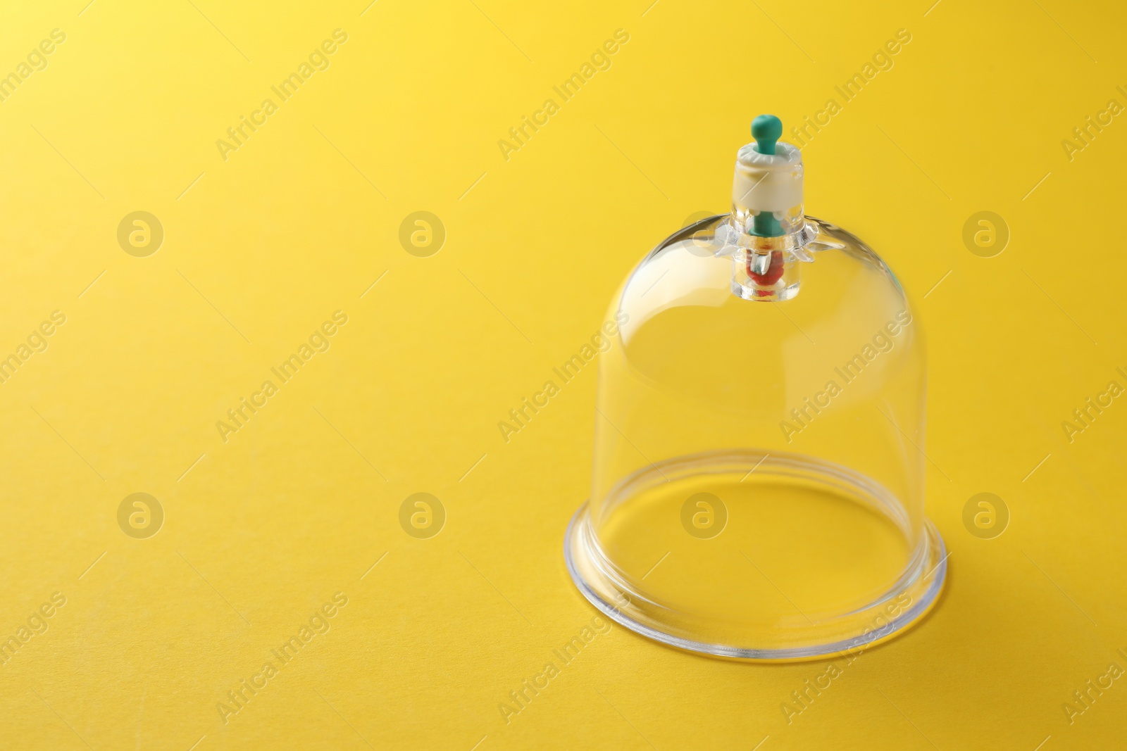 Photo of Plastic cup on yellow background, space for text. Cupping therapy