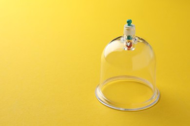 Photo of Plastic cup on yellow background, space for text. Cupping therapy