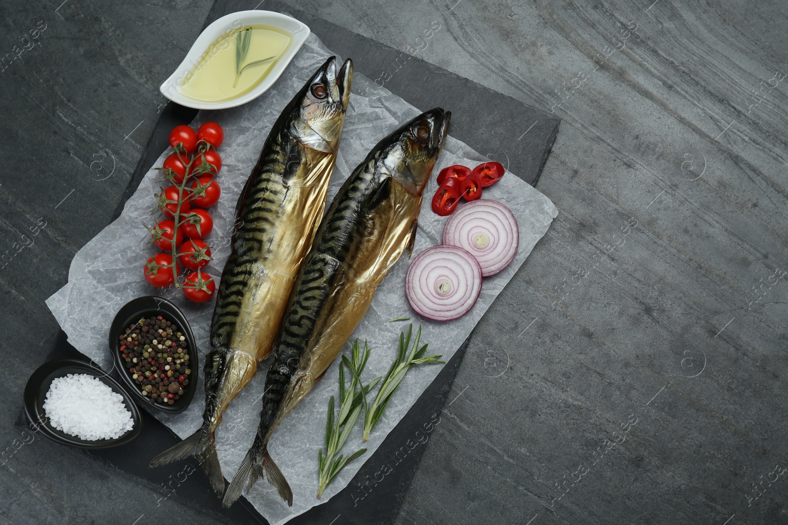 Photo of Delicious smoked mackerels and products on gray table, top view. Space for text