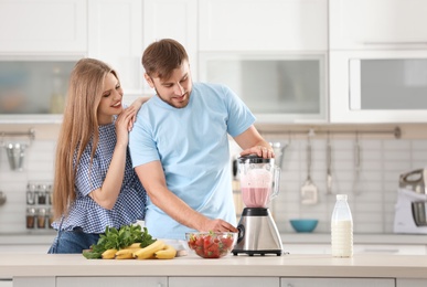 Photo of Young couple preparing delicious milk shake in kitchen