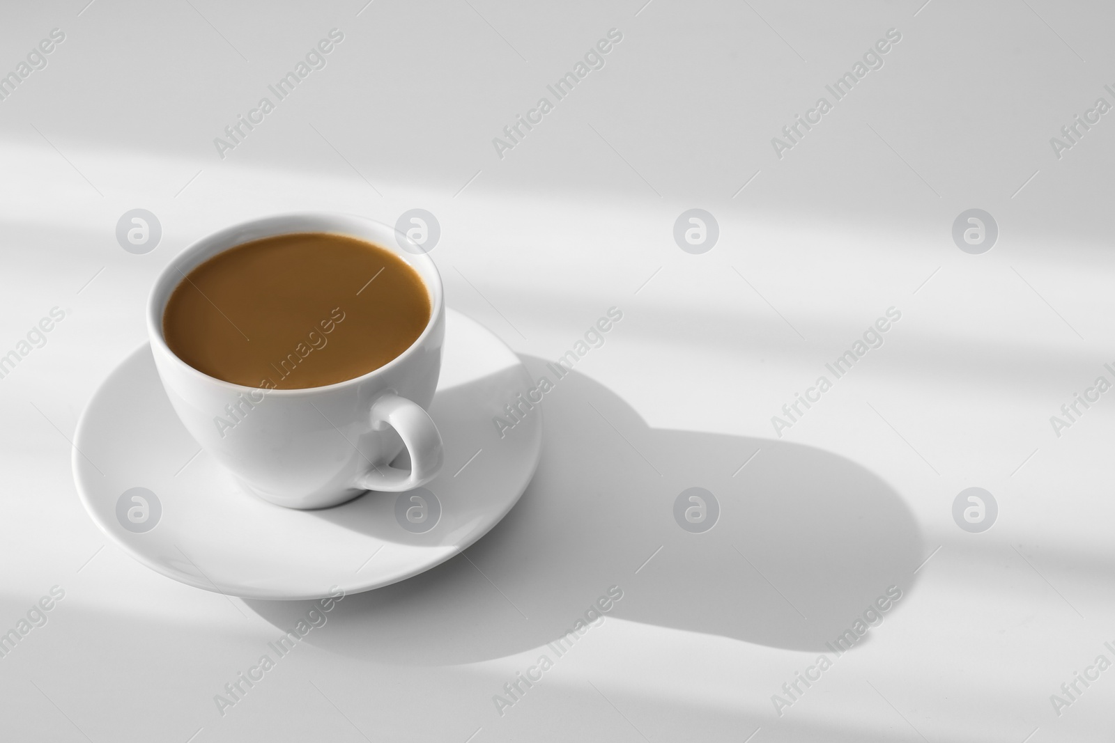 Photo of Cup of hot aromatic coffee on white table. Space for text