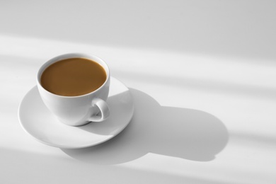 Cup of hot aromatic coffee on white table. Space for text