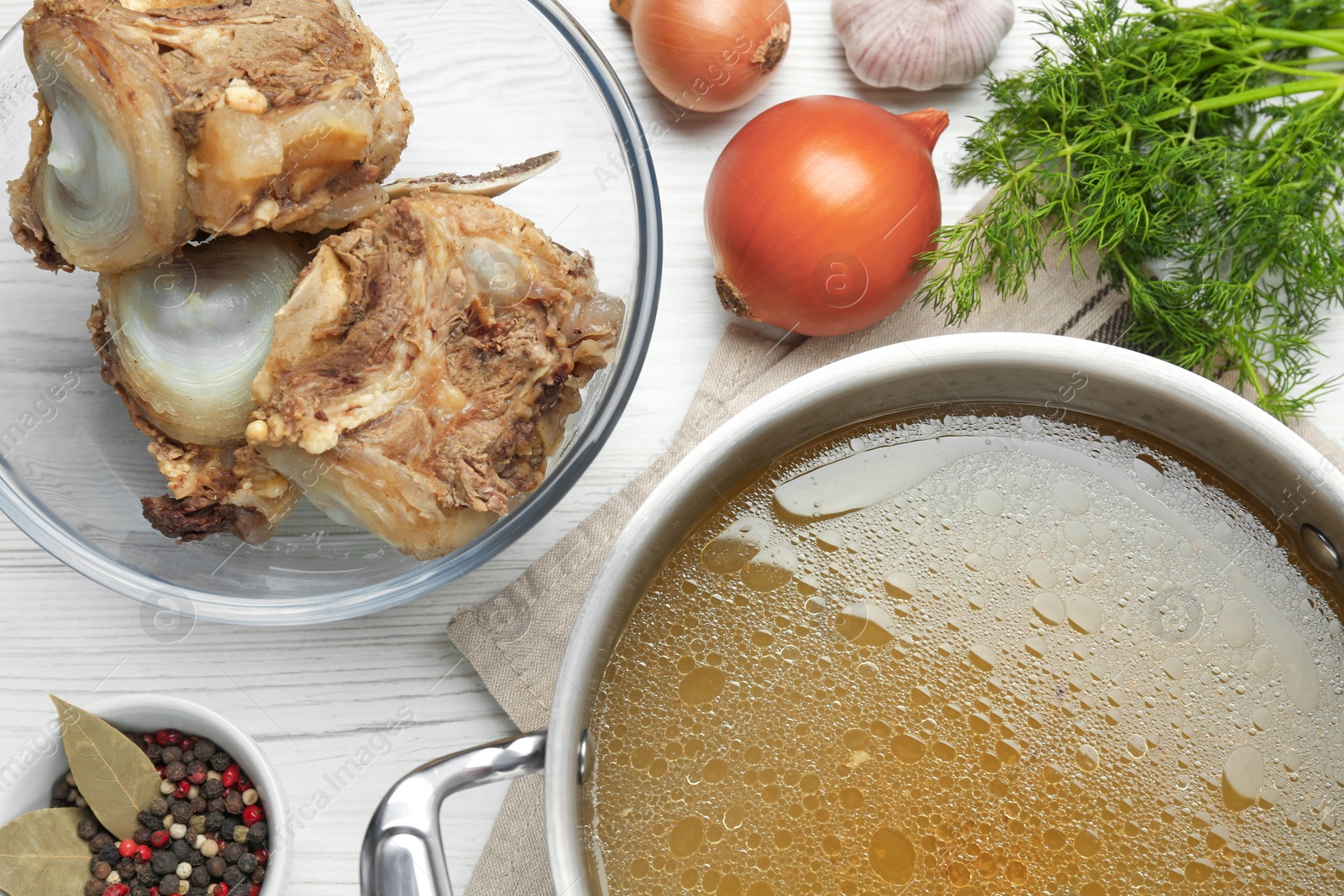 Photo of Delicious homemade bone broth and ingredients on white wooden table, flat lay