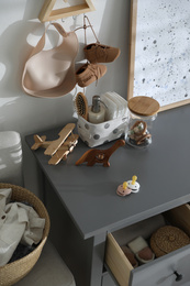 Wooden toys and different accessories on grey chest of drawers in child room