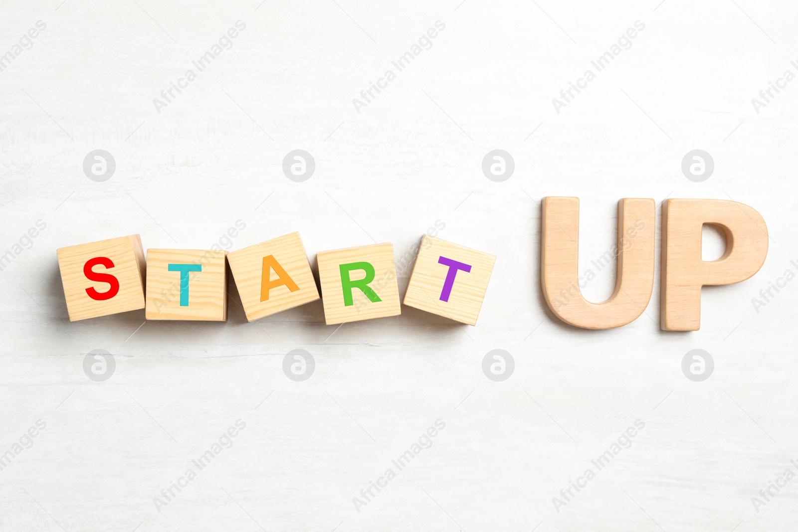 Photo of Words START UP made with wooden blocks on white background, flat lay