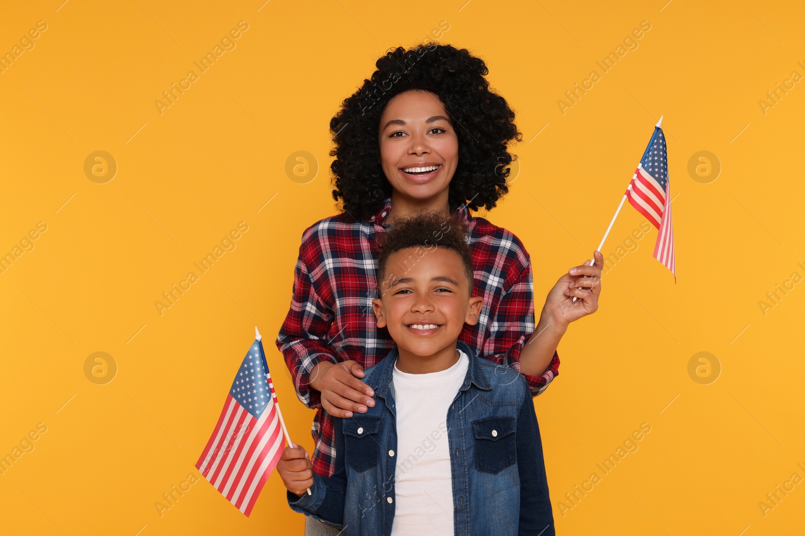 Photo of 4th of July - Independence Day of USA. Happy woman and her son with American flags on yellow background