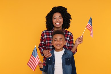 Photo of 4th of July - Independence Day of USA. Happy woman and her son with American flags on yellow background