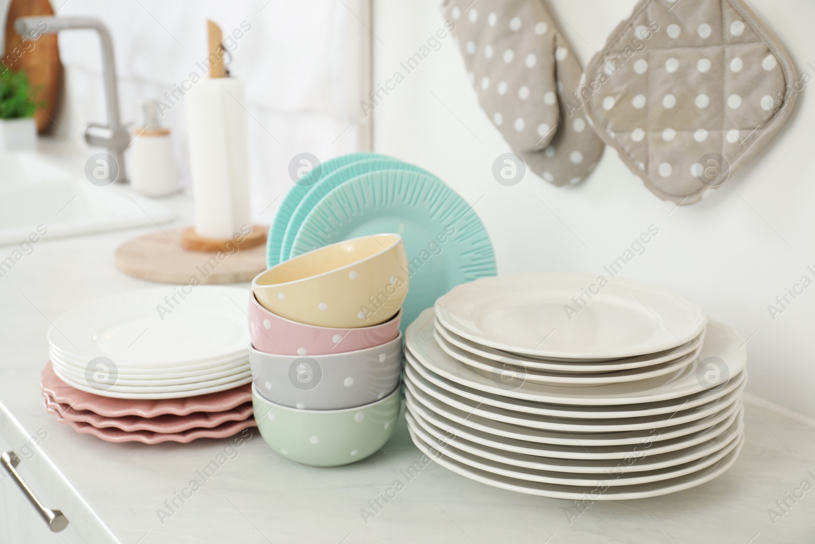 Photo of Clean plates and bowls on white marble countertop in kitchen