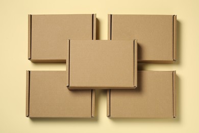 Photo of Many closed cardboard boxes on pale yellow background, flat lay
