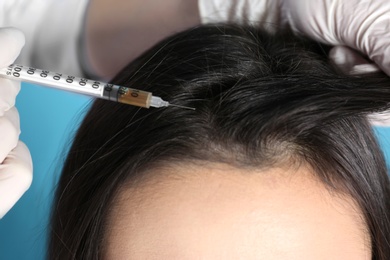 Photo of Young woman with hair loss problem receiving injection on color background, closeup