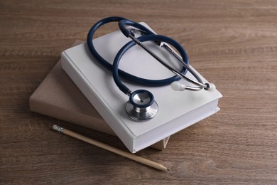 Photo of Student textbooks, pencil and stethoscope on wooden table. Medical education