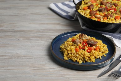 Photo of Delicious pilaf with meat, carrot and chili pepper on wooden table. Space for text