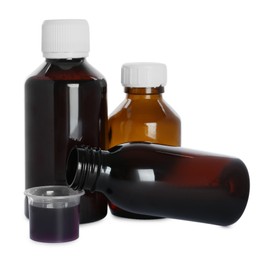 Bottles of cough syrup and measuring cup on white background