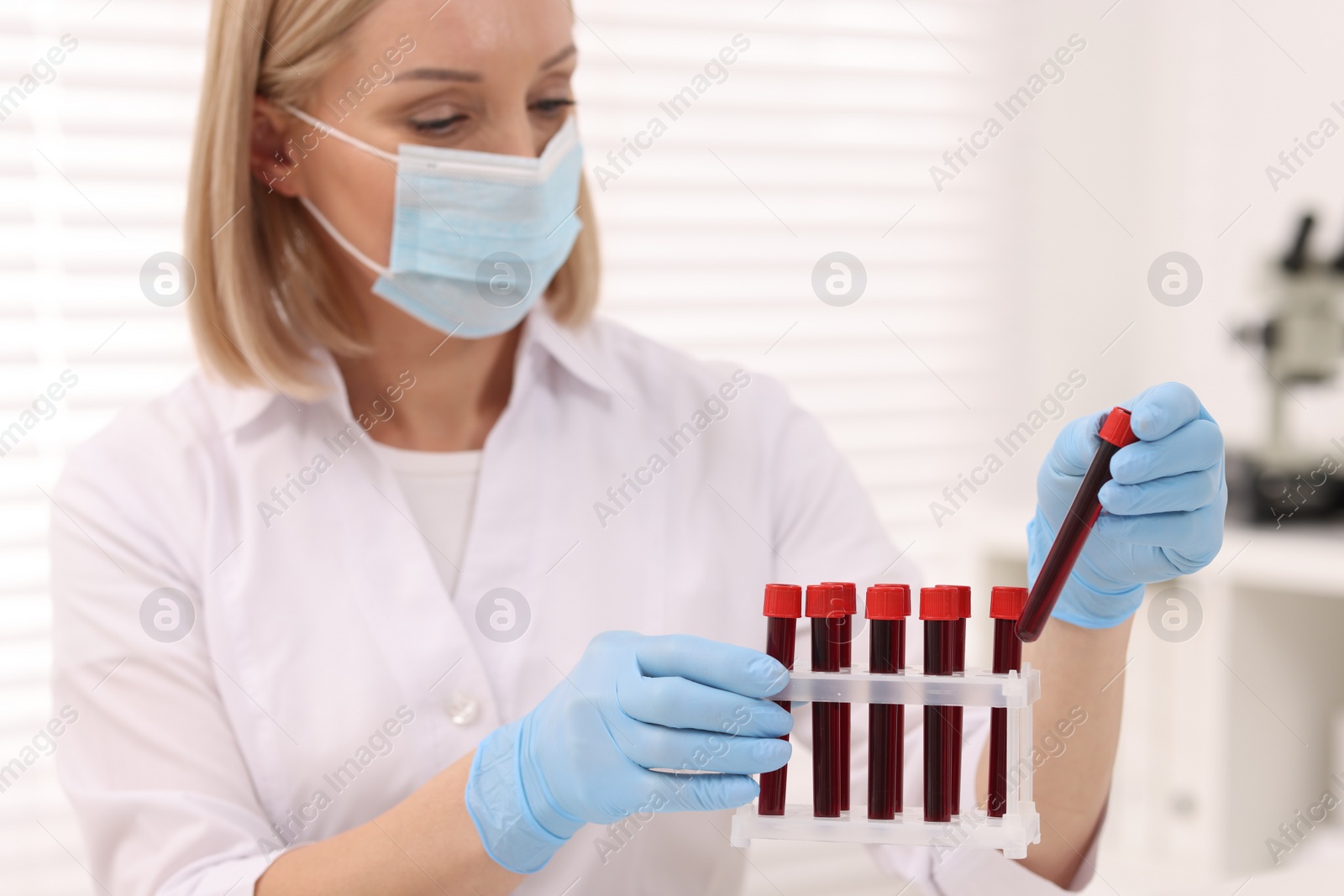 Photo of Doctor with samples of blood in test tubes at table in hospital