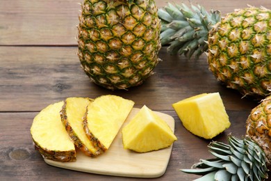 Photo of Cut and whole ripe pineapples on wooden table