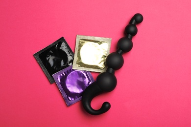 Anal ball beads and condoms on pink background, top view. Sex game