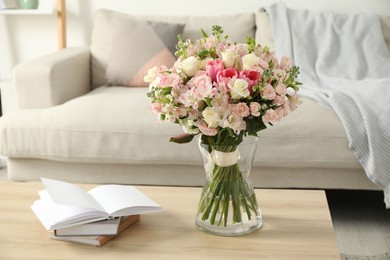 Photo of Beautiful bouquet of fresh flowers in vase and books on wooden table indoors