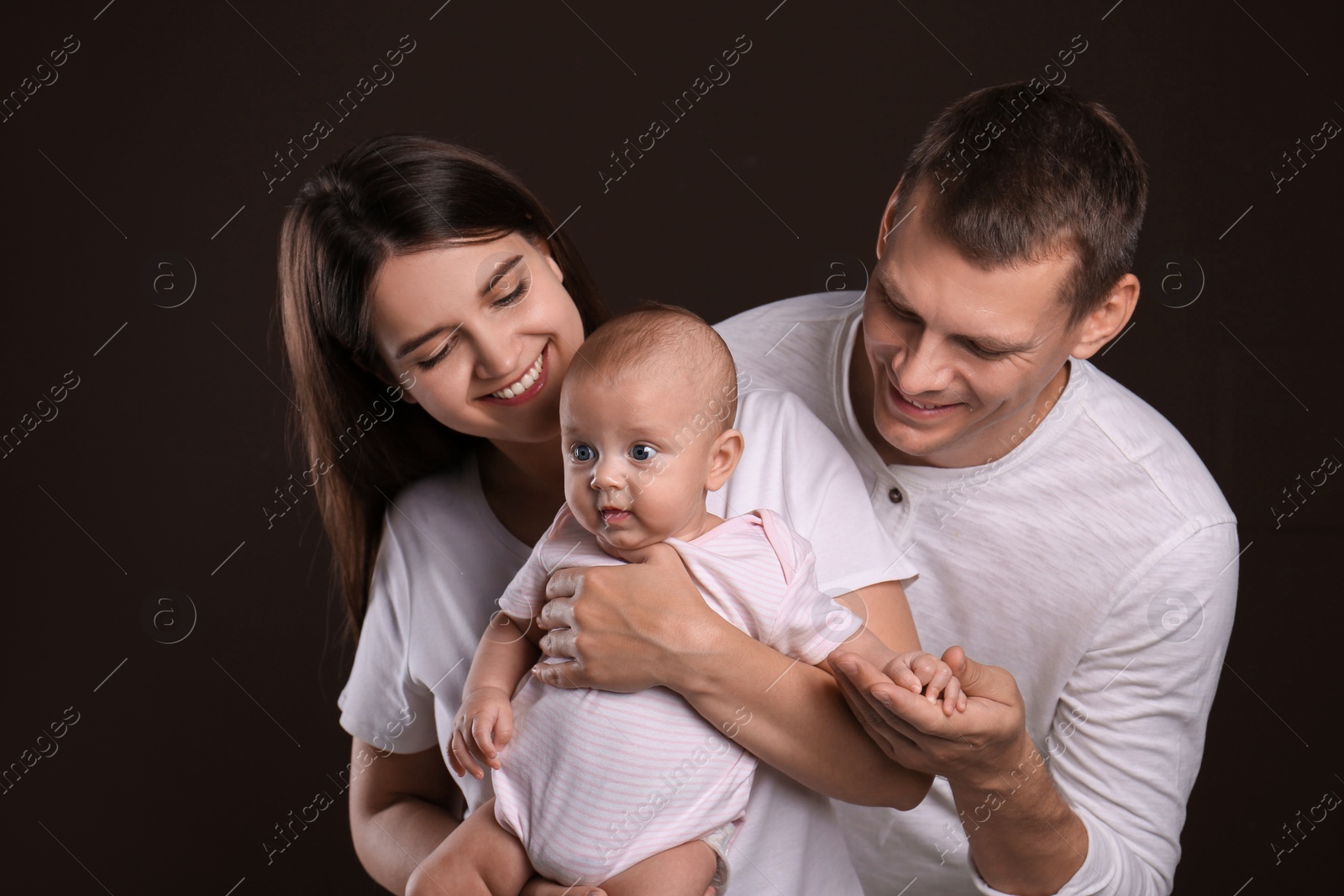 Photo of Happy family with little baby on dark background