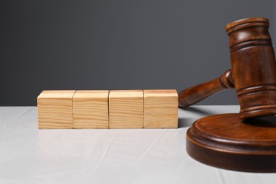 Photo of Law. Blank wooden cubes and gavel on light table against gray background