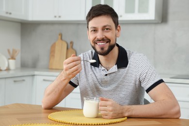 Photo of Handsome man with tasty yogurt at table in kitchen