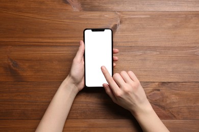 Photo of Woman using smartphone at wooden table, top view