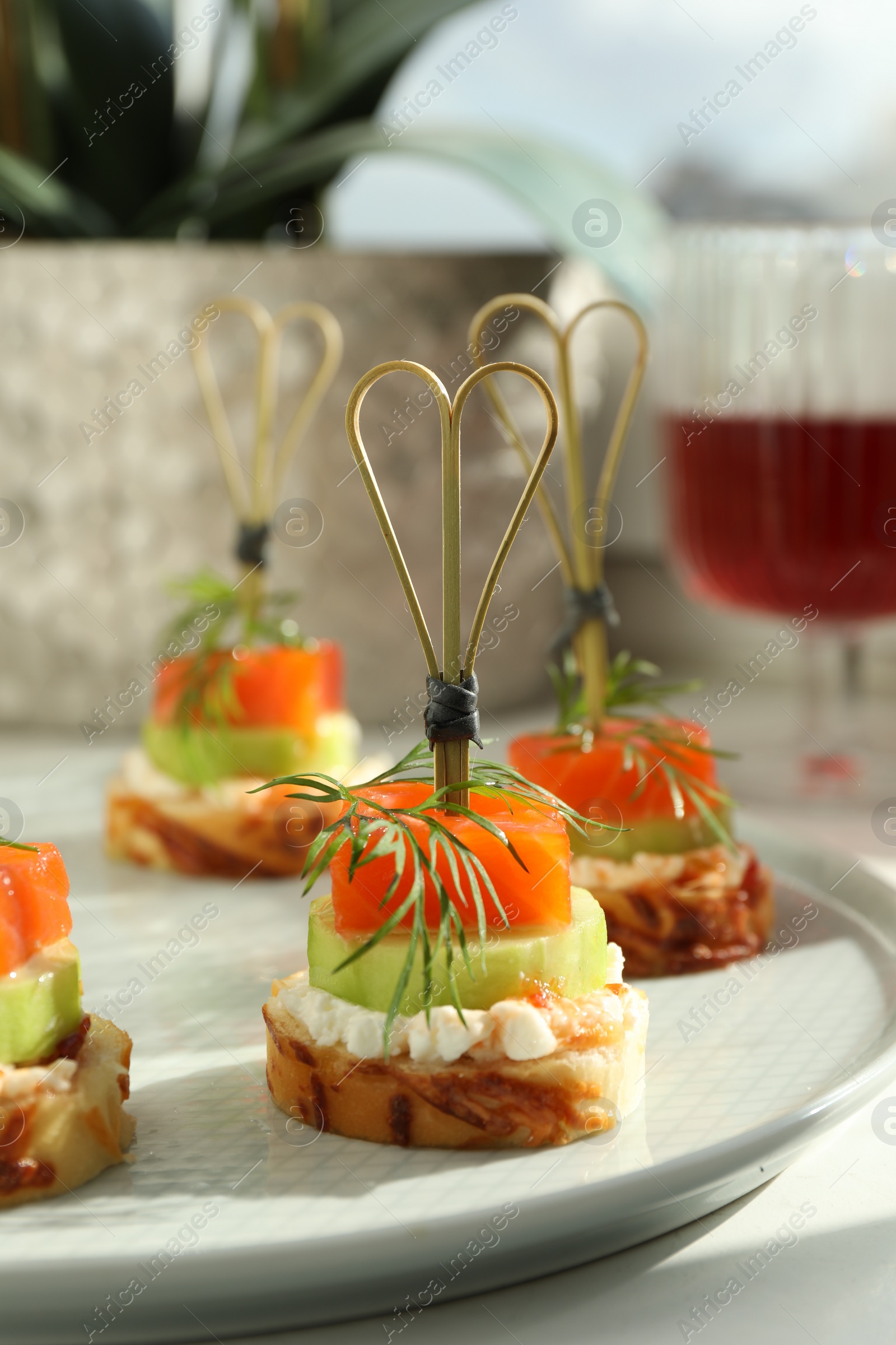 Photo of Tasty canapes with salmon, cucumber, bread and cream cheese on white table, closeup