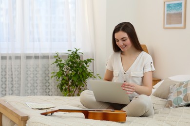 Woman learning to play ukulele with online music course at home. Space for text