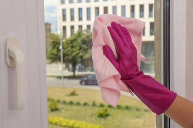 Photo of Young woman cleaning window glass with rag at home, closeup