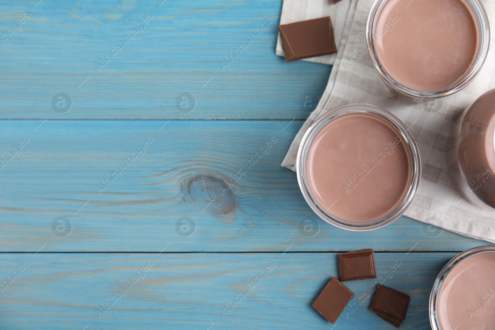 Photo of Delicious chocolate milk on light blue wooden table, flat lay. Space for text