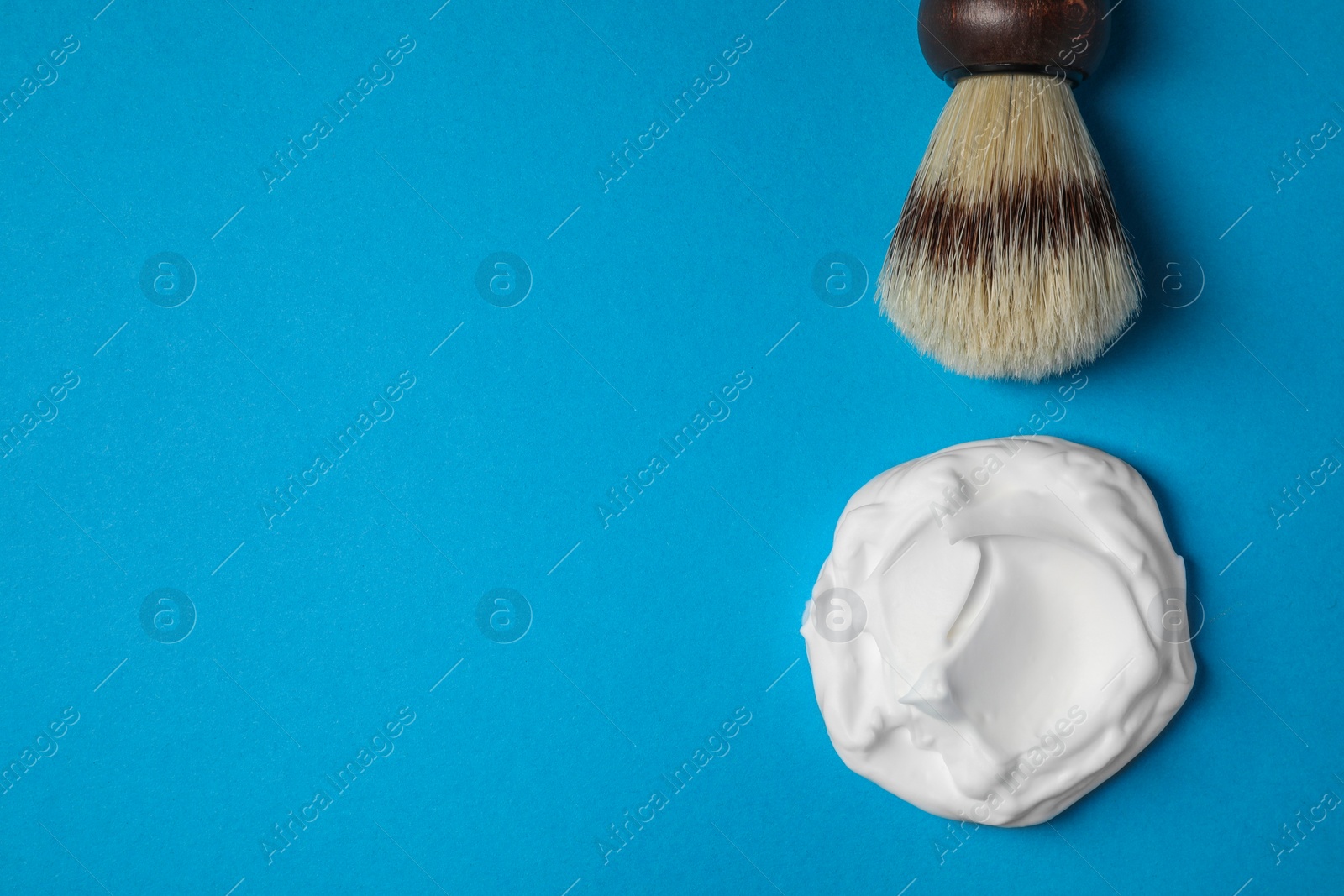 Photo of Sample of shaving foam and brush on blue background, flat lay. Space for text