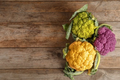 Photo of Colorful cauliflower cabbages on wooden table, top view. Healthy food