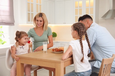 Photo of Happy family eating together at table in modern kitchen