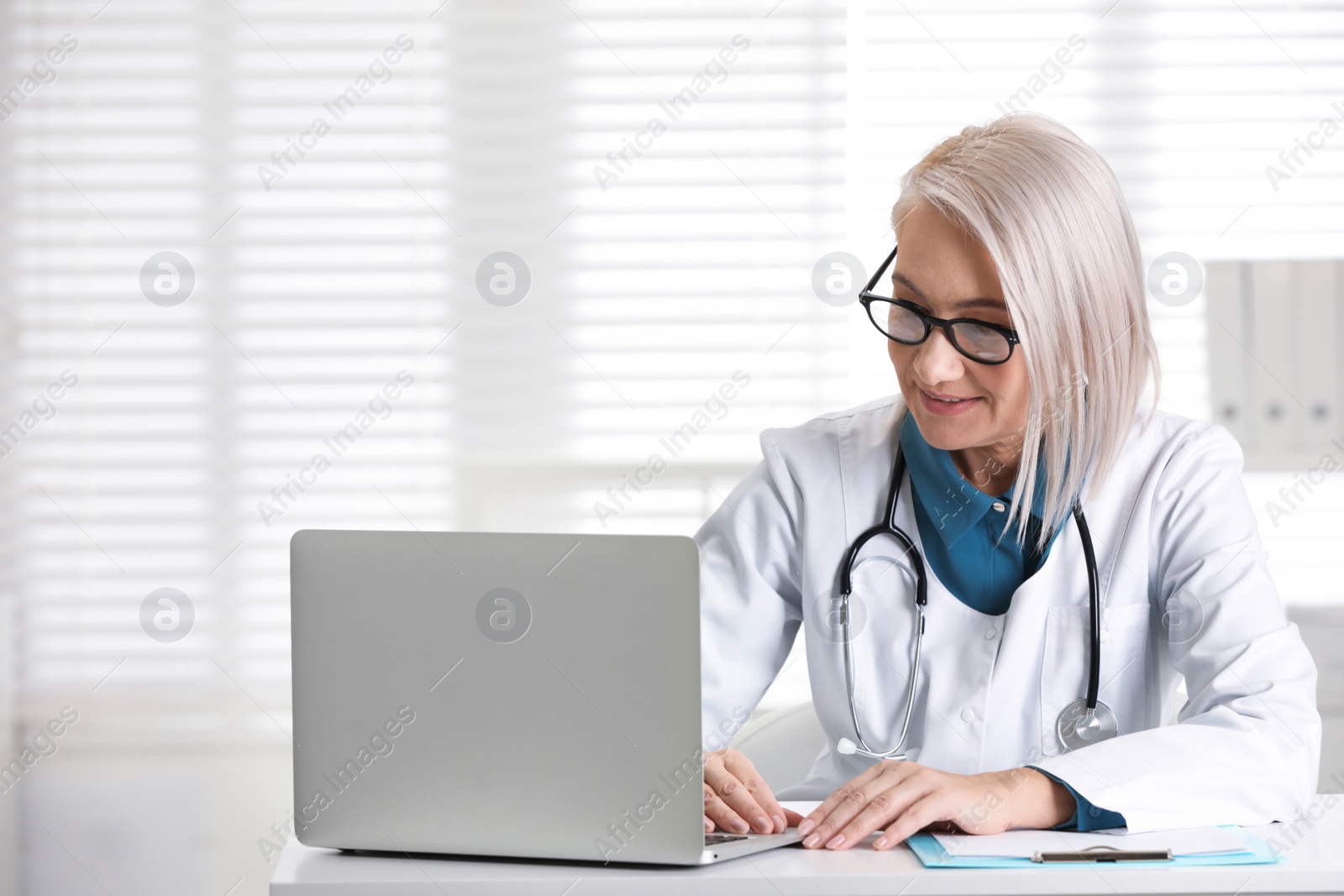 Photo of Mature female doctor working at table in office