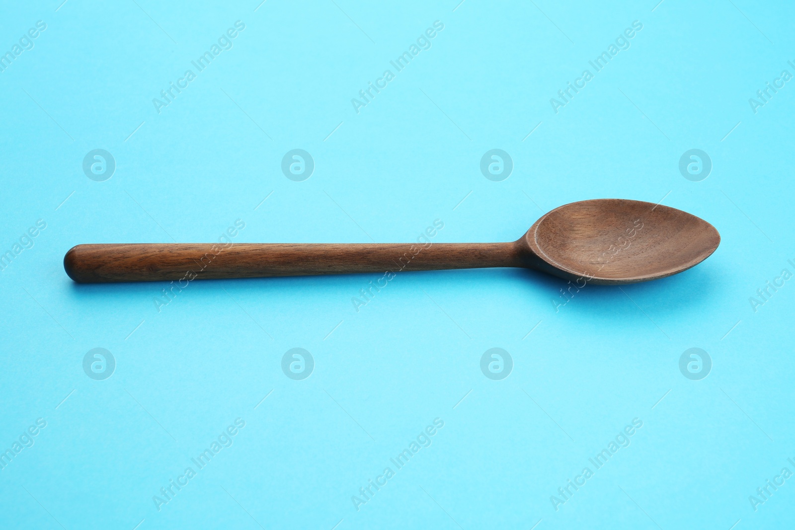 Photo of Clean empty wooden spoon on blue background