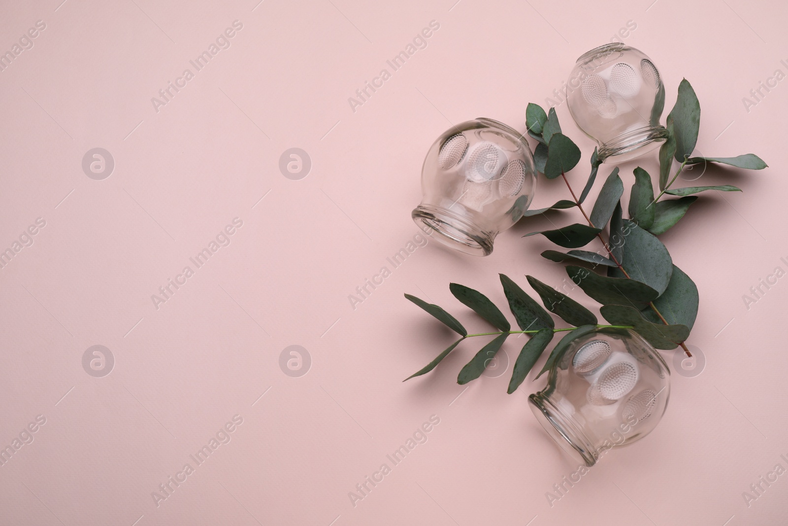 Photo of Glass cups and leaves on pink background, flat lay with space for text. Cupping therapy