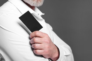 Photo of Man holding blank business card on grey background, closeup. Space for text