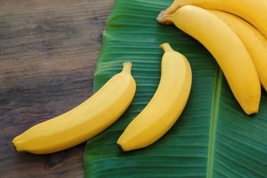 Photo of Delicious bananas and green leaf on wooden table