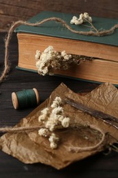 Photo of Book with flowers as bookmark on wooden table