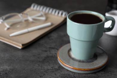 Photo of Mug of hot drink with stylish cup coaster on grey table. Space for text