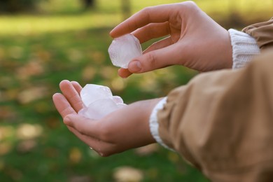 Photo of Woman holding hail grains after thunderstorm outdoors, closeup