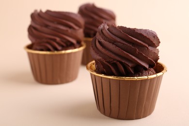Photo of Delicious chocolate cupcakes on beige background, closeup