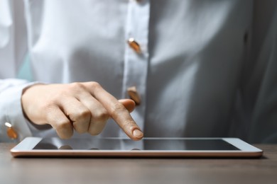 Closeup view of woman using modern tablet at table