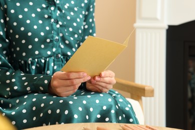 Photo of Woman holding greeting card in living room, closeup