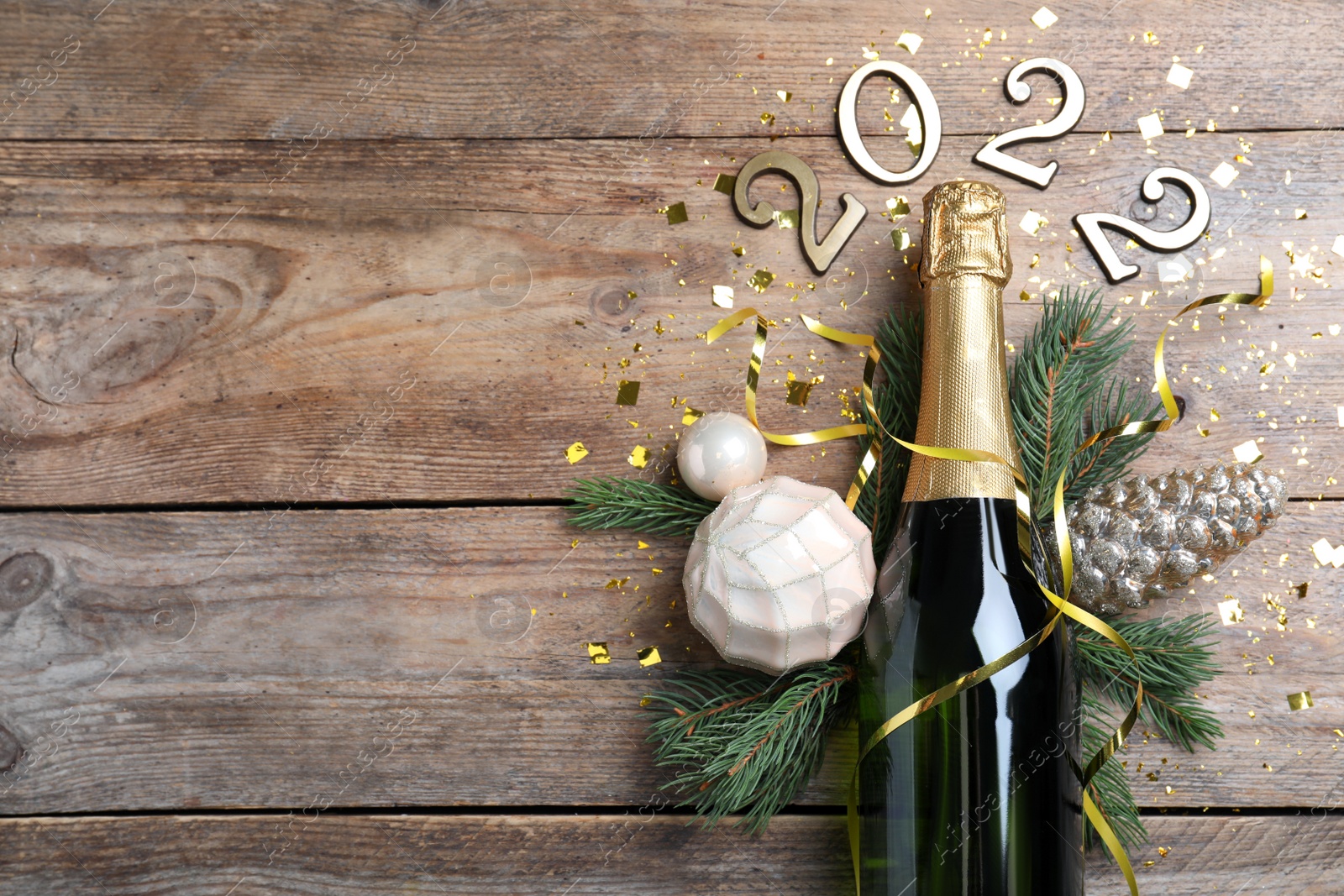 Photo of Happy New Year 2022! Flat lay composition with bottle of sparkling wine on wooden table, space for text