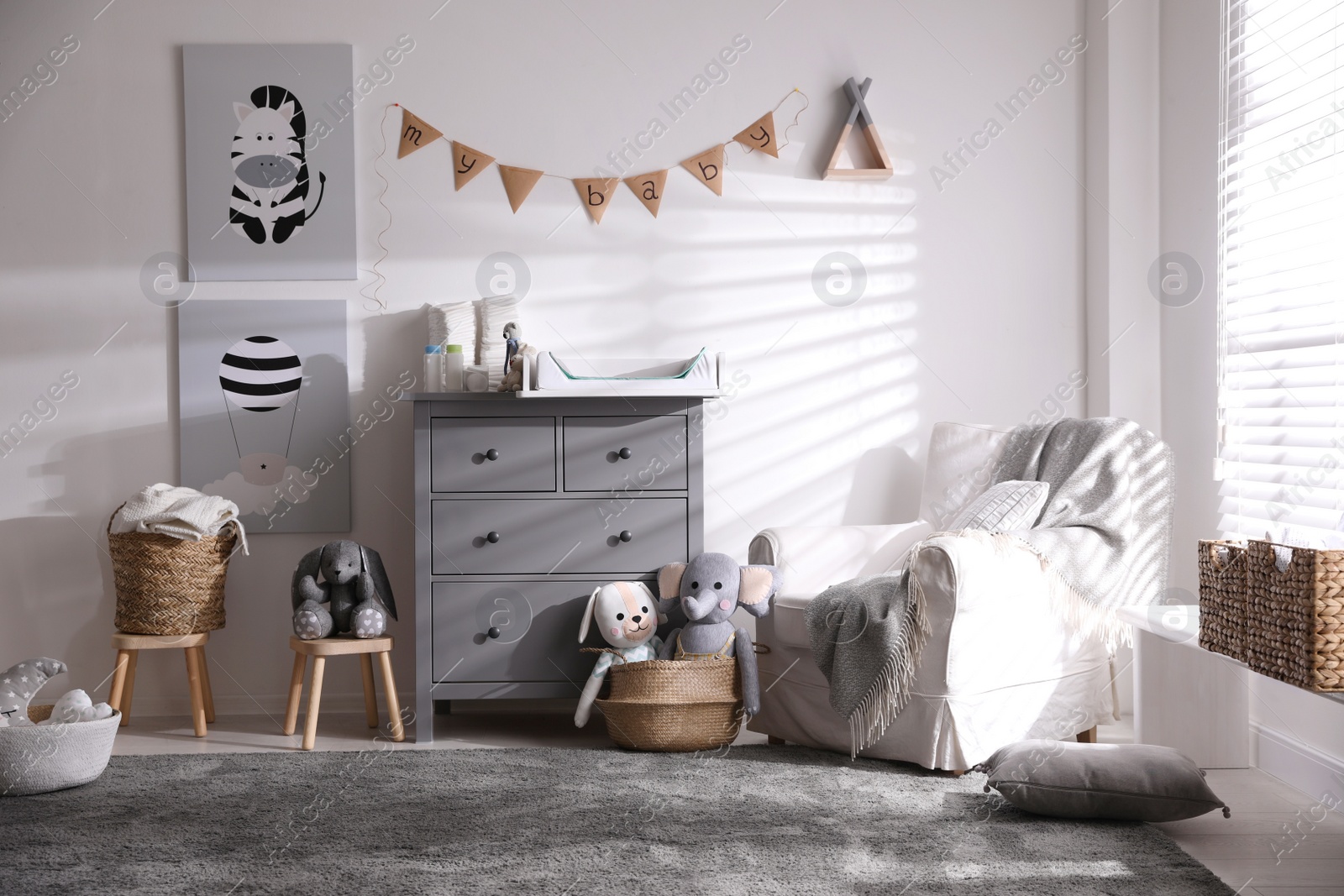 Photo of Chest of drawers with changing tray and pad in baby room. Interior design