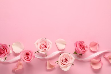 Photo of Beautiful roses, petals and ribbon on pink background, top view. Space for text